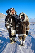Inuit women in traditional caribou clothing and sealskin boots / kamiks, Lancaster Sound, Nunavut, Canadian high Arctic, March 2004