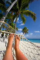 Woman tourist relaxing in hammock on tropical beach, Deadman's Bay, Peter Island, British Virgin Islands, April 2008, Model released