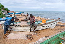 Fisherman mending gill nets on the shore of Lake Malawi, Senga Bay, Malawi. March 2009