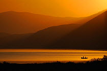 Fishermen in boat on Lake Prespa, silhouetted at sunrise, Lake Prespa National Park, Albania, June 2009 WWE BOOK. WWE INDOOR EXHIBITION