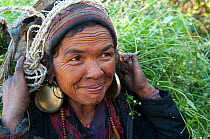Portrait of woman from Tamang ethnic group carrying grain in sack on her back. Tamang heritage trail, Gadlang, Langtang region, Nepal., November 2009