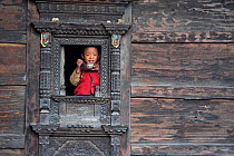 Young boy drinking tea, and looking out from window of traditional wood buildling. Tamang ethnic group, Tamang heritage trail, Thuman, Langtang region, Nepal., November 2009