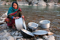 Woman washing dishes in river near Melamchi bazar, Healmbu, Nepal, November 2009