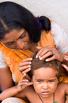 Hindi mother checking child (3 years) for head lice in home in industrial slum, Bhopal, Madhya Pradesh, India, November 2008