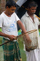 Men with crabs in net caught as part of a crab catching scheme initiated by an NGO to alleviate rural poverty, Uttaran, Ganges delta, Bangladesh, October 2008