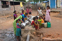 Women and children collecting clean water in industrial slum, Bhopal, India, November 2008