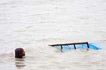 Young child up to her neck in water fishing for shrimp fry, Ganges Delta, Bangladesh, November 2008