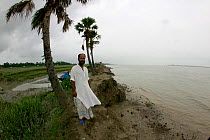 Bangladeshi man standing on edge of coast devastated by coastal erosion, Sundarbans, Ganges Delta, Bangladesh, December 2008