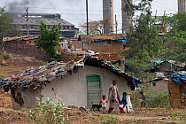 Family outside house amongst industrial pollution in slum, Bhopal, Madhya Pradesh, India, November 2008