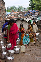 Women and children queueing to collecting clean water in industrial slum Bhopal Madyah Pradesh, India, November 2008