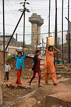 Teenagers and chidren collecting fresh water in industrial slum, Bhopal, Madhya Pradesh, India, November 2008
