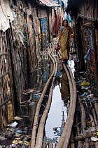 Woman walking through polluted slum, Dhaka, Bangladesh, July 2008