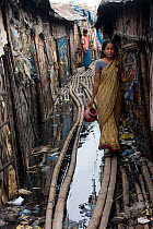 Woman walking through polluted slum, Dhaka, Bangladesh, July 2008