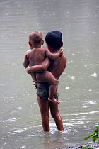 Young Bangladeshi with young brother in monsoon rain washing in pond, Ganges delta, Bangladesh, November 2008