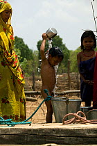 Hindu woman washing son at well, village life, Madhya Pradesh, India, November 2008
