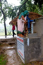 Woman collecting water from pump at clean water project initiated by NGO, Uttaran, Ganges delta, Bangladesh, November 2008