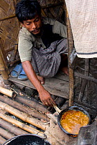 Bangladeshi man cooking in slum, Dhaka, Bangladesh, November 2008