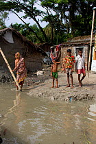 Villagers outside home threatened by rising sea level, Ganges delta, Bangladesh, November 2008