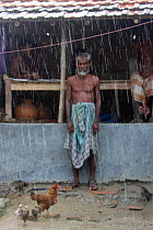 Monsoon rain, with man and chickens, Ganges delta, Bangladesh, November 2008