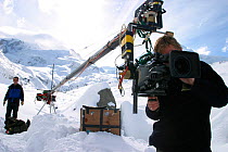 Cameraman, Ted Giffords, checks the settings on the HD camera before the team swing the camera on a 6 metre jib arm out over ice caves in the glacier, with rope safety expert, Tim Fogg, behind, for th...