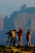 Cameraman, Ted Giffords and other crew standing on the edge of 300m high cliffs in the Simien Mountains filming the dawn light hitting the escarpment, for the Mountains episode of the BBC tv series Pl...
