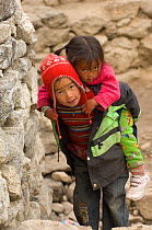 Nepalese boy giving girl a piggy back ride to young girl, Sagarmatha National Park, Khumbu, Himalayas, Nepal, November 2007