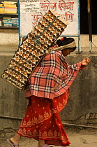 Woman walking to the market carrying eggs on her back with head strap, Kathmandu, Nepal, December 2007