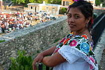 Maya woman in traditional dress looking down at large wedding ceremony, Izamal, Yucatan, Mexico