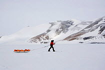Woman pulling her man haul pulk along the base of Patriot Hills, West Antarctica, January 2006.