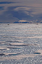 Snow patches on blue ice at the foot of Patriot Hills with orographic cloud formation over the Ellsworth Mountains. Antarctica, January 2006.
