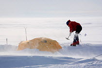 Shovelling snow from mountain tent in the wind. Patriot Hills. Antarctica, January 2006.