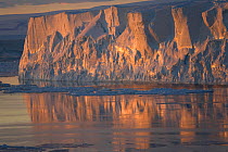 Textured tabular iceberg reflecting in the Weddell Sea at sunset. Antarctica, October 2006.