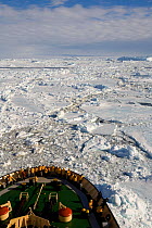 Yellow jacketed tourist on the bow of the "Kapitan Khlebnikov" venturing through pack ice in Erebus & Terror Gulf. Antarctica, October 2006.