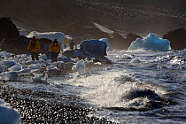 Tourists walking amongst ice blocks in the surf on Brown Bluff Beach, Southern Ocean, Antarctica, October 2006.