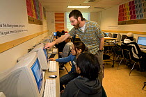 IT teacher helps inuit pupil with computer studies. Igloolik, Nunavut, Canada. April 2008. Model released.