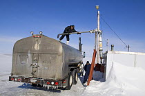 Inuit men filling tanker from the frozen water reservoir near Igloolik. Nunavut, Canada, April 2008.