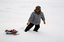 Inuit boy from Pangnirtung, playing on the ice with a toy snowmobile. Nunavut, Canada, April 2008.