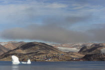 Iceberg floating by the Inuit village of Scoresbysund on the coast of Scoresbysund Fjord. East Greenland, September 2005.