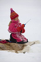 Young girl ice fishing on a lake near Kautokeino. Finnmark, North Norway, March 2007.