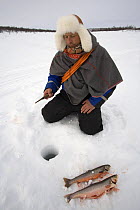 Saami reindeer herder ice fishing for Arctic Char on a lake near his reindeers' winter pastures. Kautokeino, Finnmark, North Norway, March 2007.
