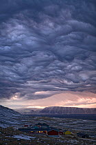 Dramatic 'Undulatus asperatus' cloud formation as a storm builds at dawn over Qaanaaq, Inglefield Bay. Northwest Greenland, September 2008. This cloud formation was first proposed as a new type of clo...
