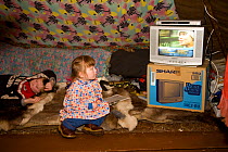 Young Khanty girl watching TV in her parent's tent at their winter reindeer pastures. Yamal, Western Siberia, Russia. Editorial use only.