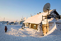 Snow covered wooden house with satellite dish in winter in the Nenets village of Nahodka. Gydan Peninsula, Yamal, Western Siberia, Russia.
