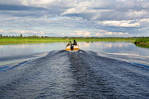 Selkup man and his son travelling by boat on the Puryakhar River near Bistrinka. Purovsky Region, Yamal, Western Siberia, Russia, August 2008.