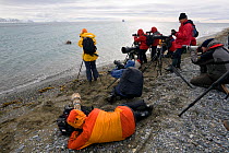 Group photographing a Walrus (Odobenus rosmarus) in the shallows. Prins Karls Forland, Spitsbergen, Svalbard, Norway, June 2008.