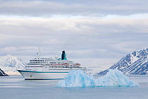 500 berth cruise ship "Albatros" by a small blue iceberg in Lilliefjorden. Spitsbergen, Svalbard, Norway, June 2008.