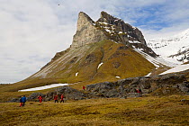Tourists visiting the bird cliffs of Alkehornet, made from folded and metamorphosed limestone. Spitsbergen, Svalbard, Norway, June 2006.