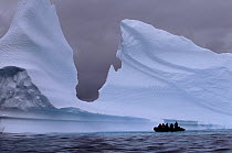 Tourist zodiac is dwarfed by the huge icebergs near Pleneau Island, Antarctic Peninsula.
