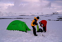 Two people dismantling their tent at Weincke Island, Antarctica.