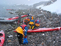 Kayakers on the beach in a snow flurry. Antarctica, February, 2004.